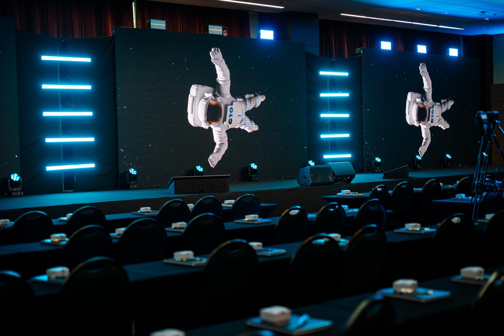 Auditório de evento corporativo com palco, painéis de LED e plateia