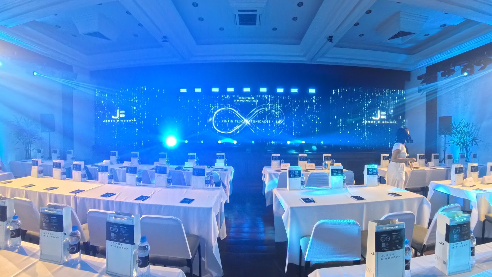 Palco corporativo com painel LED ao fundo e plateia organizada em evento de franqueados