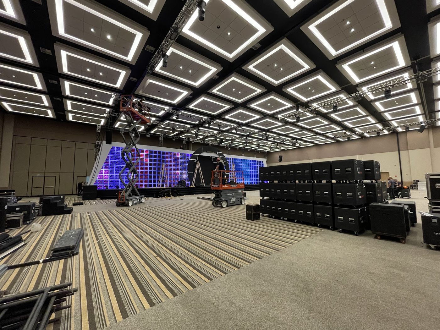 Plataformas elevatórias e painel LED sendo posicionado durante montagem de evento corporativo