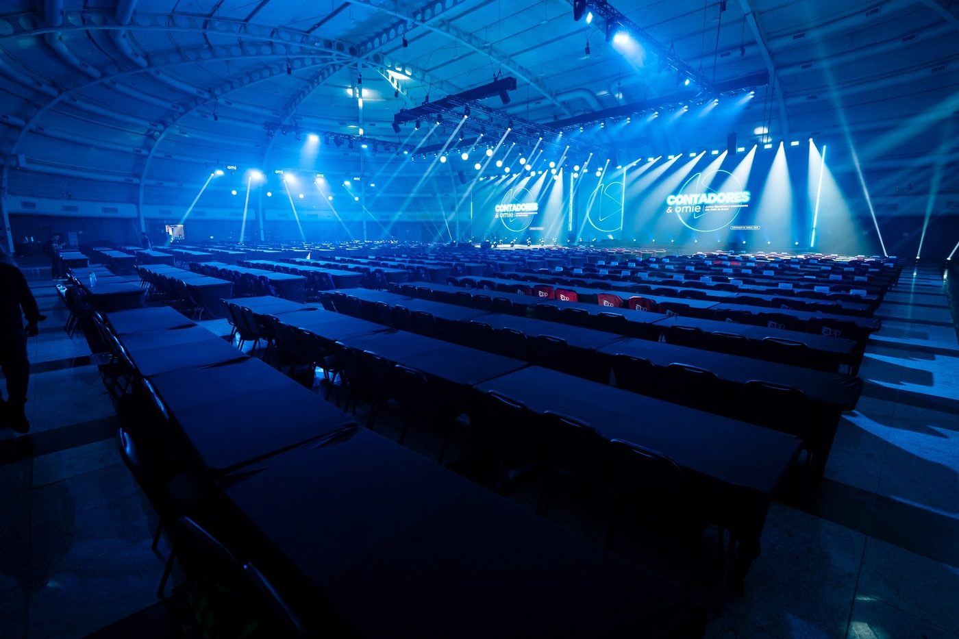 Palco da Convenção de Vendas Omie 2026 com painéis de LED e feixes de luz no WTC Events Center