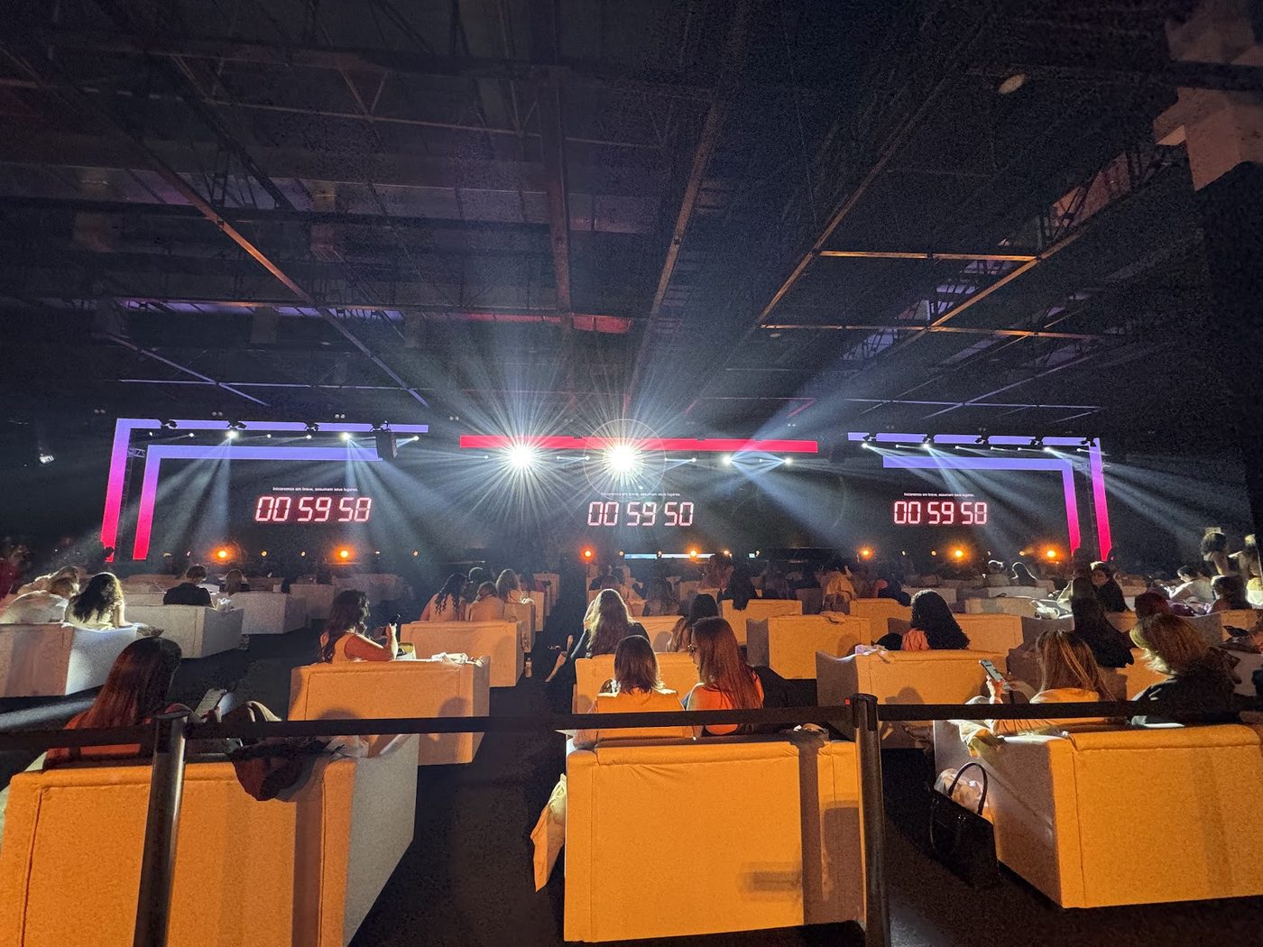 Auditório corporativo com feixes de luz coloridos, telões de LED e poltronas para plateia