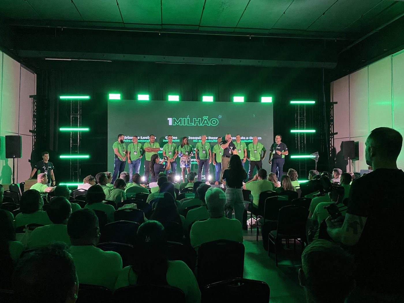 Palco de premiação corporativa com cenografia verde, treliça e telão de LED ao fundo