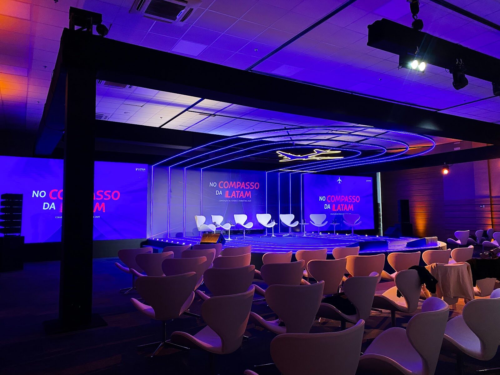 Palco corporativo com arcos de LED e ambientação em tons de azul e roxo